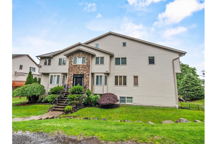 View of front of home featuring stairway and stone siding