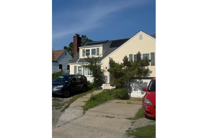View of front of property with solar panels, a shingled roof, and a chimney