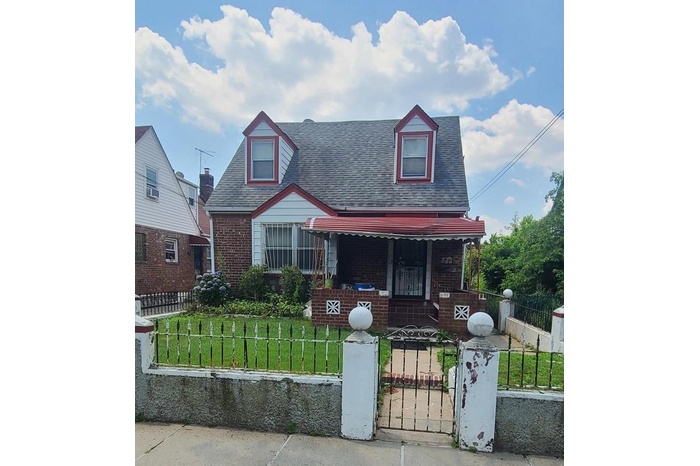 View of front of property with covered porch, brick siding, roof with shingles, and a fenced front yard
