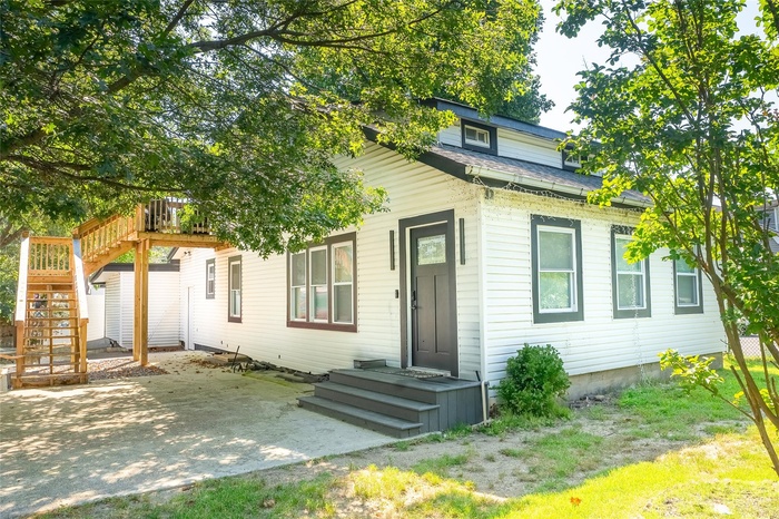 View of front facade featuring roof with shingles, a deck, stairs, and a patio area