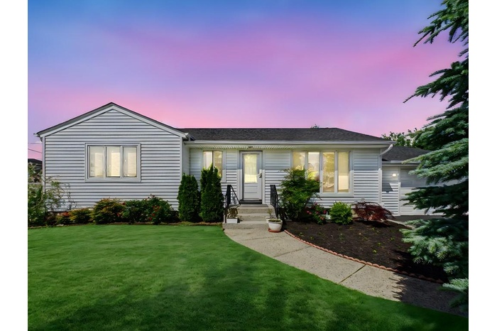 Ranch-style home featuring a front lawn and roof with shingles