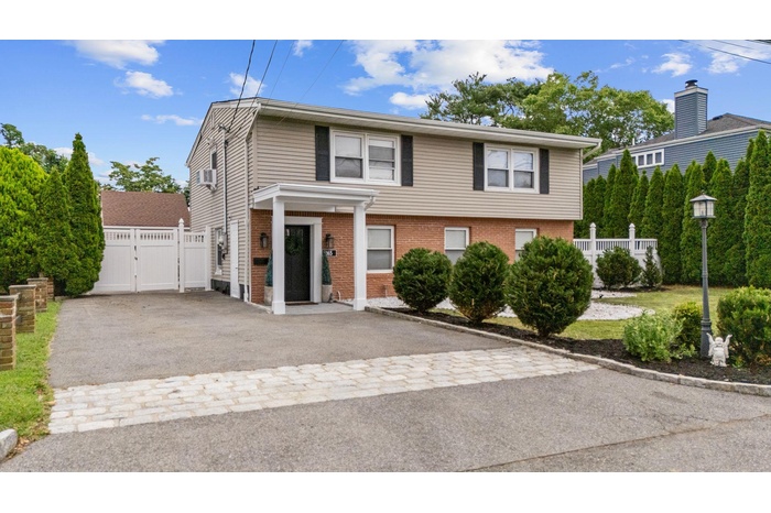 View of front of home with a gate, brick siding, and driveway