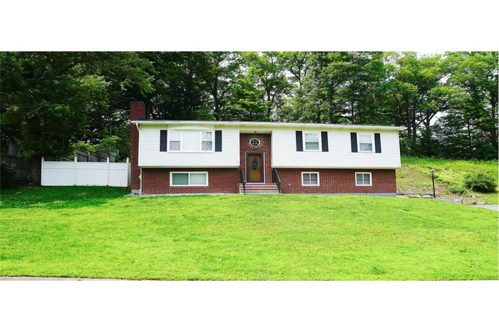 Split foyer home with a chimney, brick siding, entry steps, and view of scattered trees