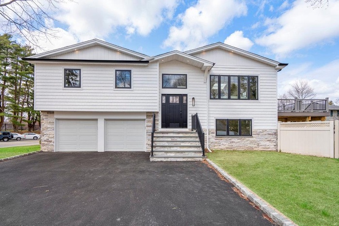 Split foyer home featuring stone siding, driveway, and an attached garage