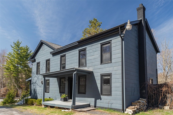 View of front facade featuring covered porch and a chimney