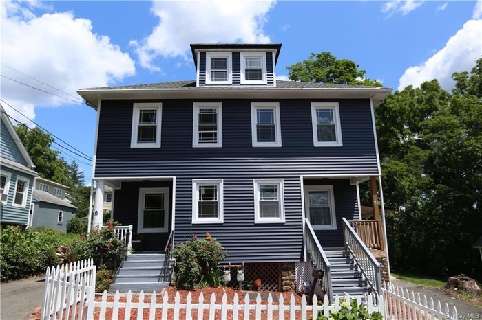 American foursquare style home featuring a porch and a fenced front yard