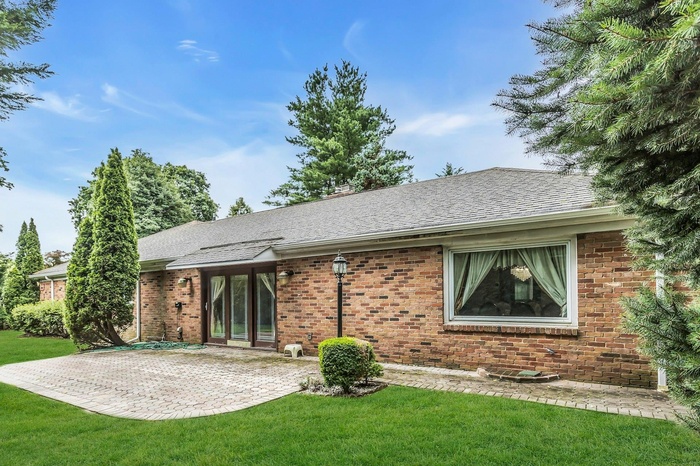 Rear view of house featuring a shingled roof, a patio area, a lawn, and brick siding