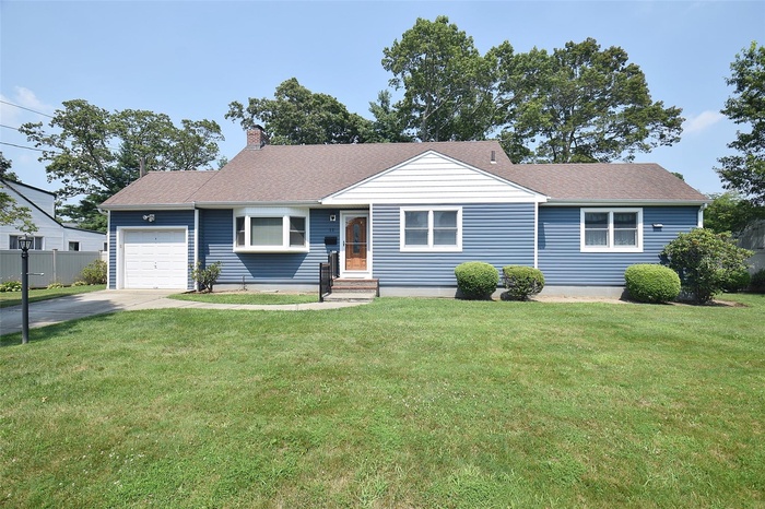 Ranch-style home with driveway, a garage, a chimney, and a shingled roof