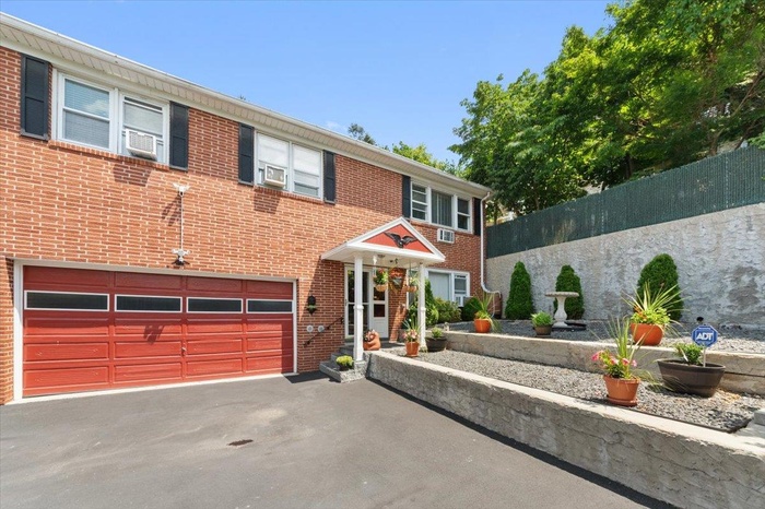 View of front of house with a garage, brick siding, and driveway