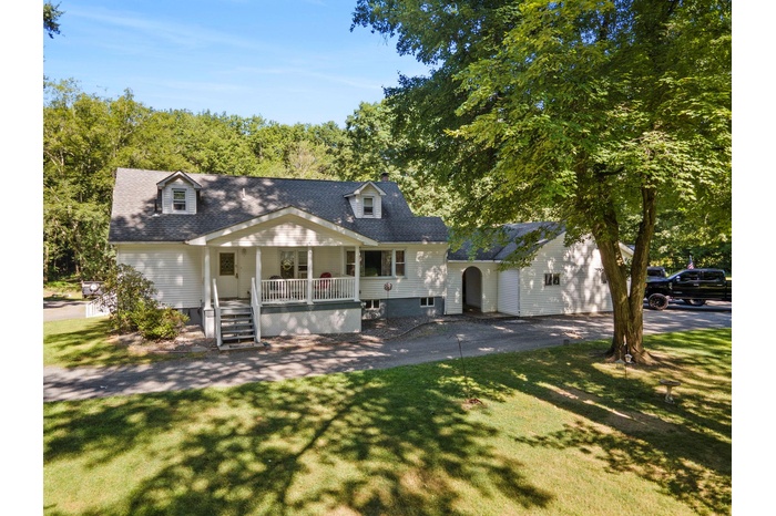 Cape cod home featuring a porch, a front yard, and a garage