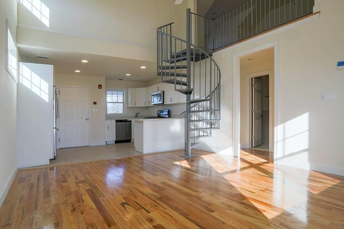 Unfurnished living room featuring light wood-style flooring, stairs, recessed lighting, and a towering ceiling