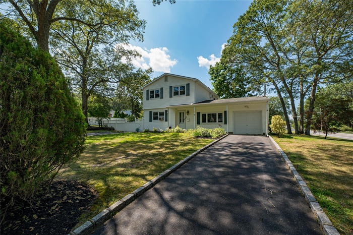 View of front facade with driveway, an attached garage, and a front lawn