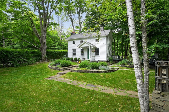 View of front of house with a chimney and a front lawn