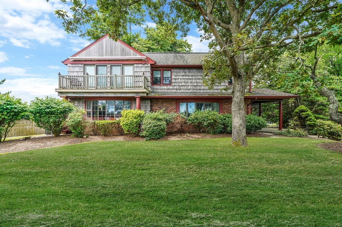 View of front of home with a balcony and brick siding