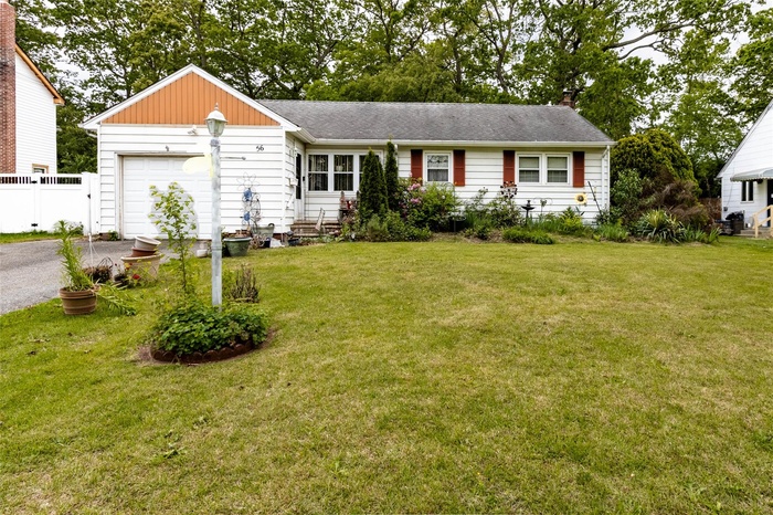 View of front of property featuring driveway, a garage, roof with shingles, and a chimney