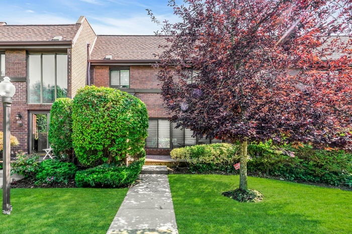 View of front of home with a front lawn, brick siding, and a shingled roof