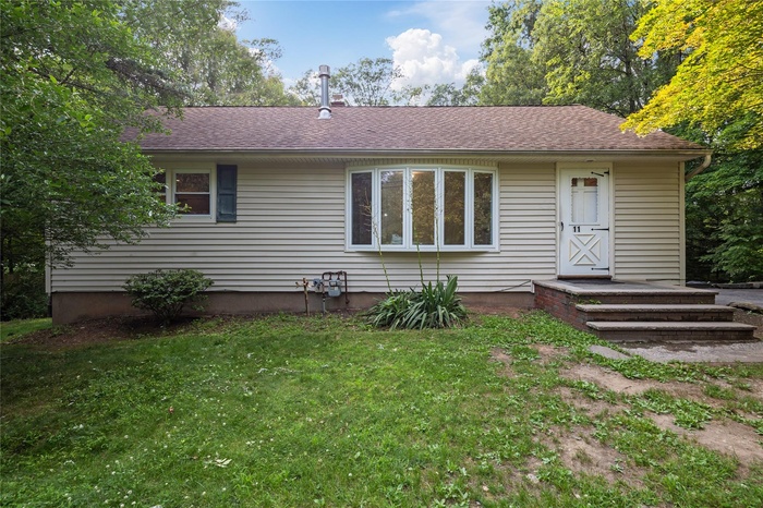 Back of property with a shingled roof and a yard