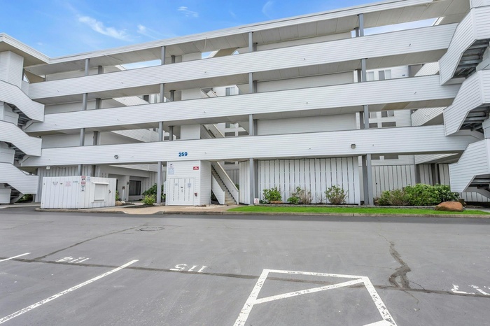 View of building exterior with uncovered parking and stairs