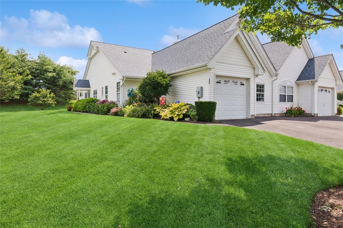 View of home's exterior with an attached garage, roof with shingles, a yard, and driveway