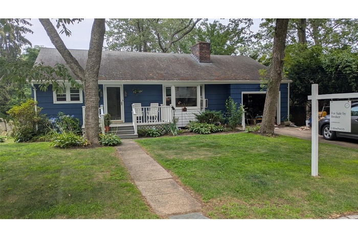 View of front of house with a porch, a front lawn, and a chimney