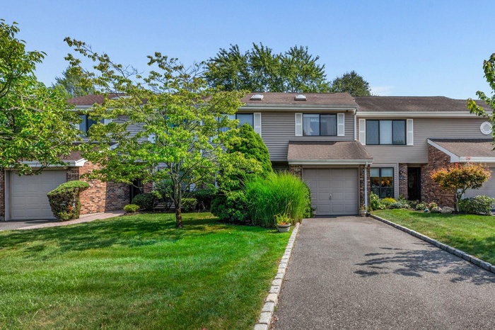 Traditional-style home with brick siding, asphalt driveway, a front yard, and an attached garage