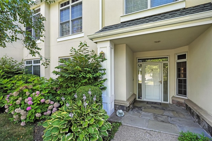 Doorway to property featuring stucco siding and a shingled roof