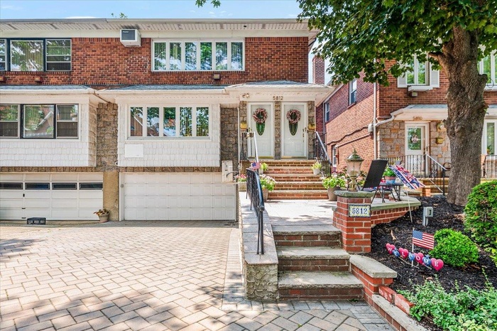 View of front facade featuring decorative driveway, an attached garage, and brick siding