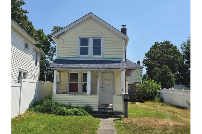 View of front of home featuring a chimney and a shingled roof