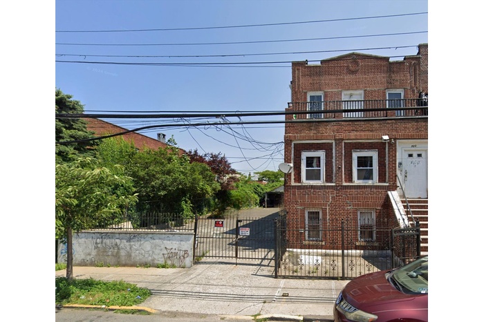 Vacant lot on the left of the brick structure