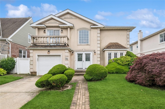 View of front of property featuring a balcony, a garage, stucco siding, and concrete driveway
