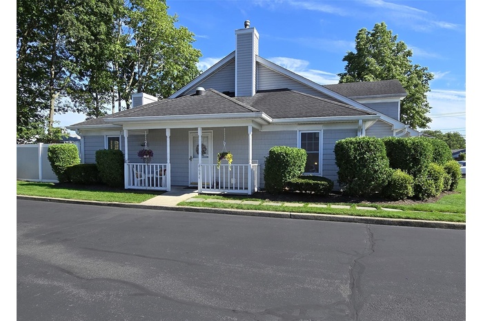 View of front of house with a chimney, a porch, and a shingled roof