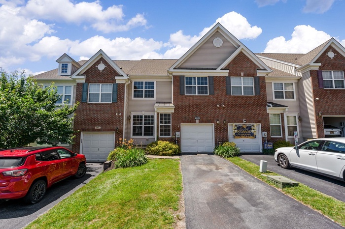 View of property featuring driveway, brick siding, and a garage