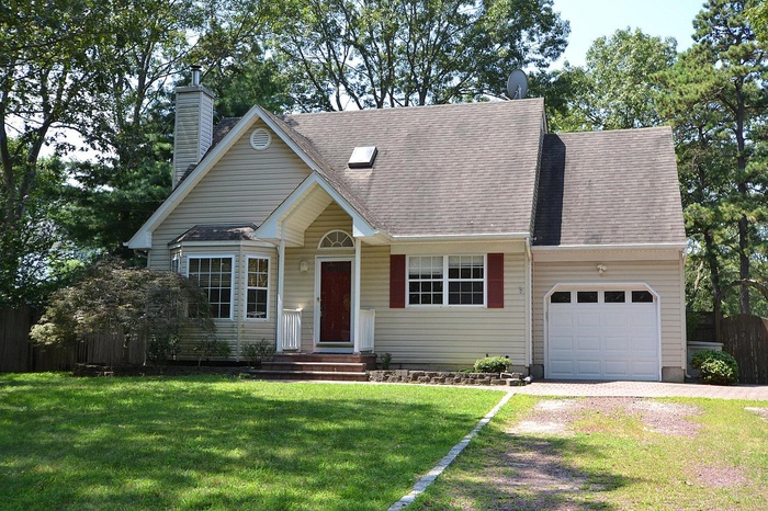 View of front of property with an attached garage, driveway, a chimney, and roof with shingles