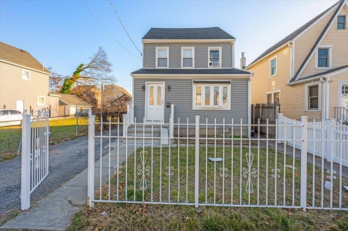 View of front facade featuring a gate, a fenced front yard, and roof with shingles