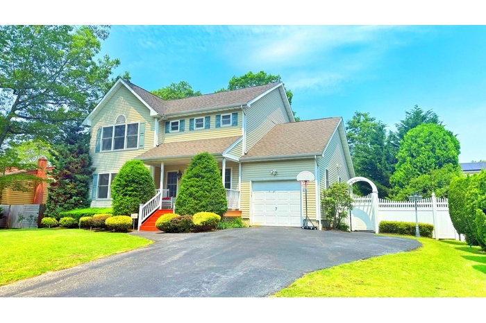 View of front of house featuring a garage, asphalt driveway, a porch, and roof with shingles
