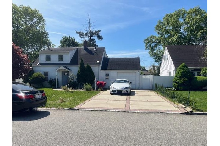 Traditional-style home with driveway, a chimney, an attached garage, and a gate