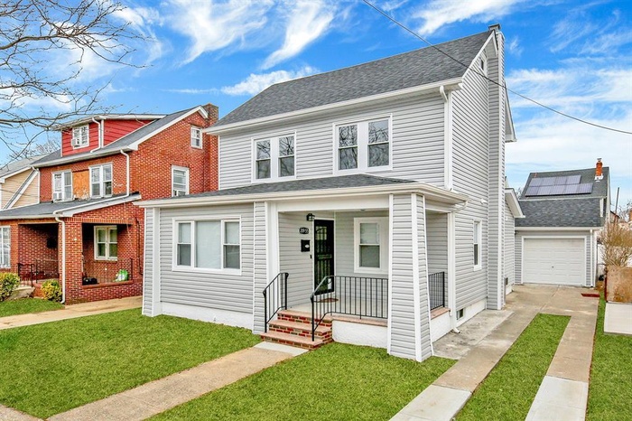 View of front of house featuring concrete driveway, a front lawn, a garage, and a porch