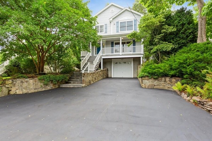 View of front of house with stairs, a porch, asphalt driveway, and a garage
