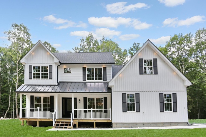 View of front of house featuring a porch, a front yard, a standing seam roof, a metal roof, and a shingled roof