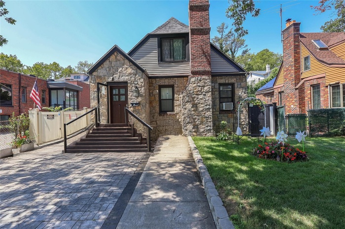 View of front of home with stone siding and a chimney