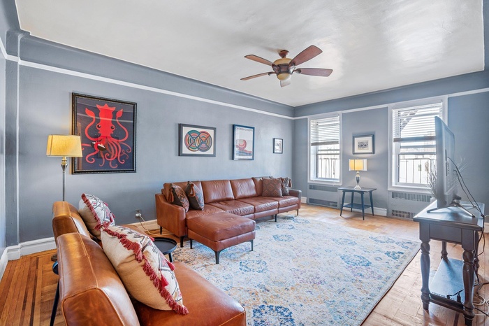 Living room with baseboards, a ceiling fan, and radiator heating unit