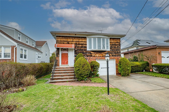 View of front of house with a front lawn, an attached garage, brick siding, and concrete driveway