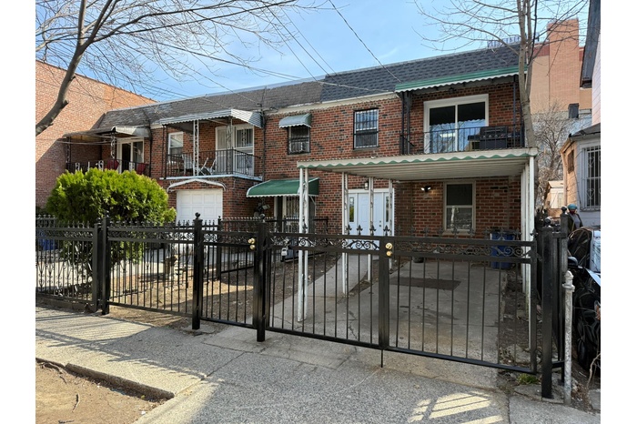 Townhome / multi-family property featuring brick siding, roof with shingles, a fenced front yard, and an attached garage