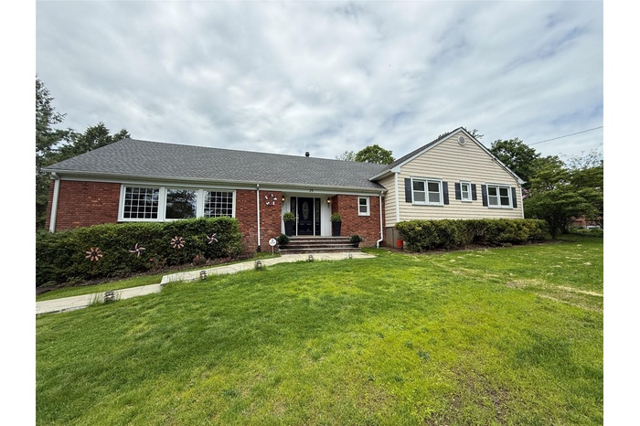 View of front of house featuring brick siding, a front yard, and roof with shingles