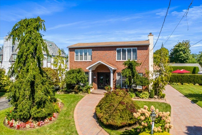View of front of property with brick siding, a chimney, and a front lawn