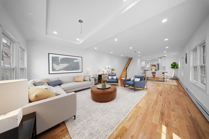 Living area featuring baseboard heating, light wood-style floors, stairs, recessed lighting, and a healthy amount of sunlight