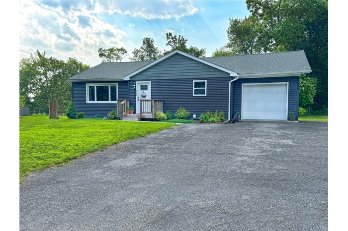 Single story home with a garage, driveway, a front yard, and roof with shingles