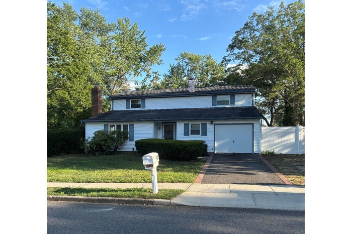 Traditional home with a chimney, asphalt driveway, and a garage