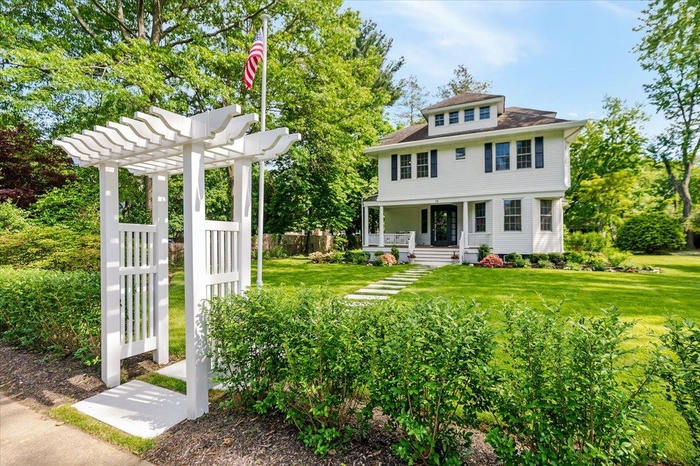 View of front of house featuring covered porch, a pergola, and a front yard
