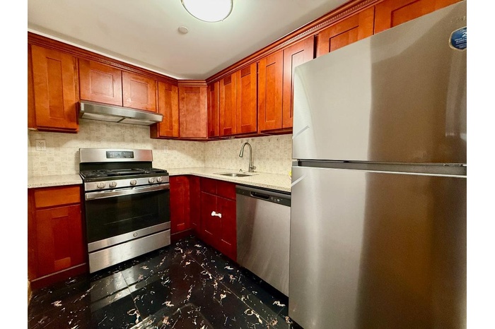 Kitchen featuring appliances with stainless steel finishes, under cabinet range hood, a sink, and light countertops